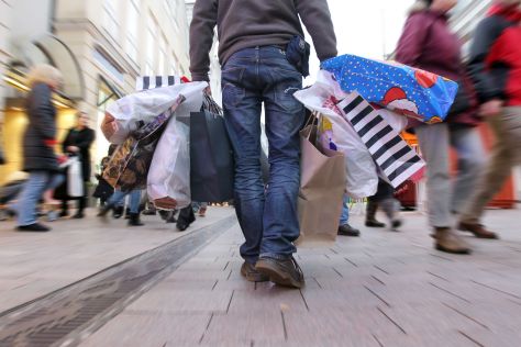 Ein Mann geht mit Tüten schwer bepackt durch eine Fußgängerzone
